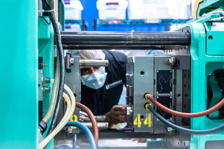 Engineer looking into injection molding machine to view parts being produced and molded