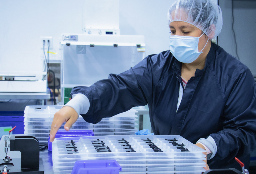 Cleanroom operator picking up assembled devices after complex assembly process