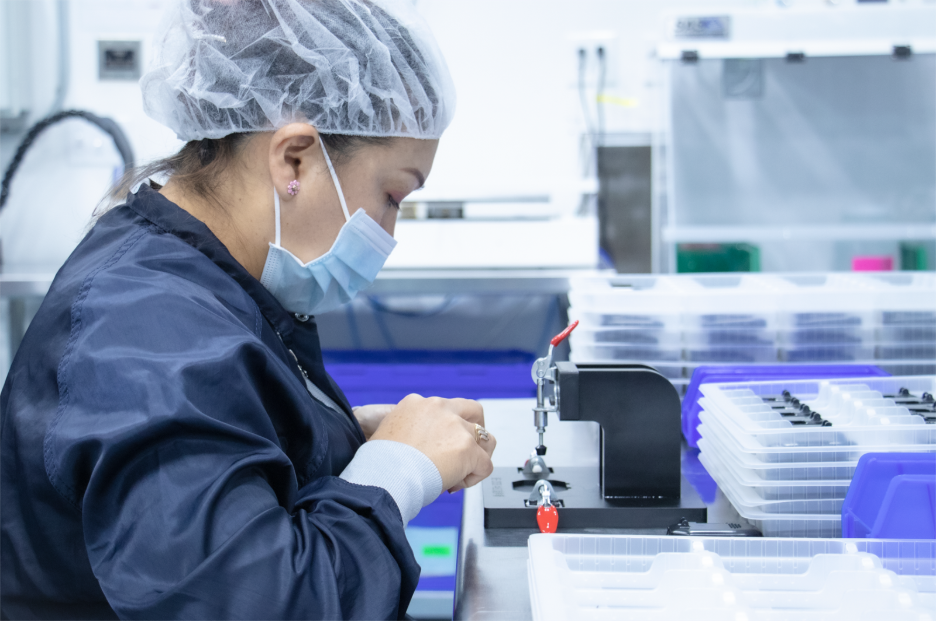 Technician manually assembling medical device components in a cleanroom, highlighting the limitations of manual assembly at scale.